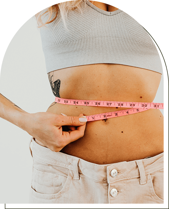 A woman is measuring her waist with a tape measure.