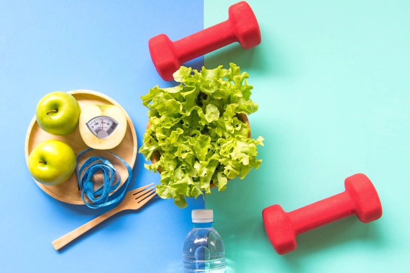 A table topped with lettuce and red dumbbells.
