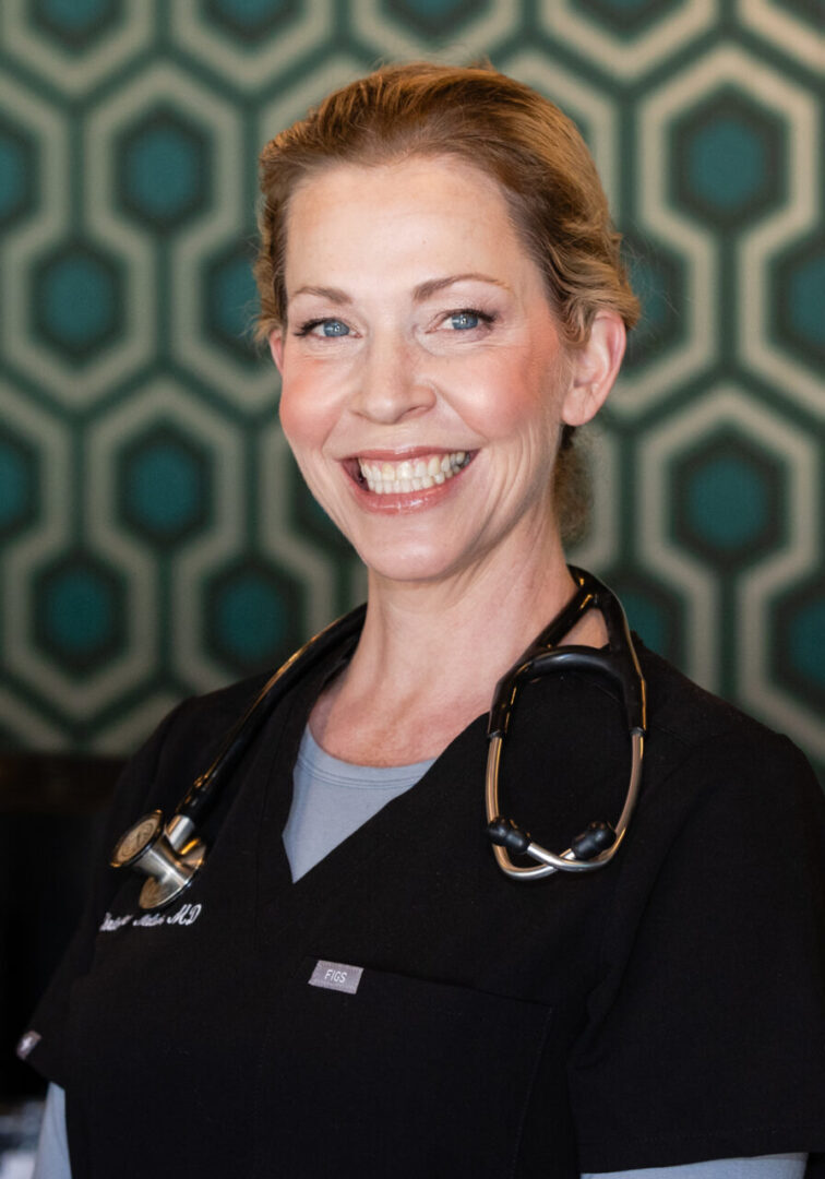 A woman in scrubs smiling for the camera.