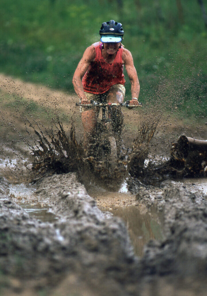 A man riding a dirt bike through mud.